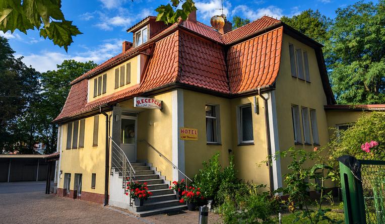 Zabytkowa fasada willi Hotel Pod Platanami z dojrzałymi platanami przy cichej ulicy w Trzebnicy